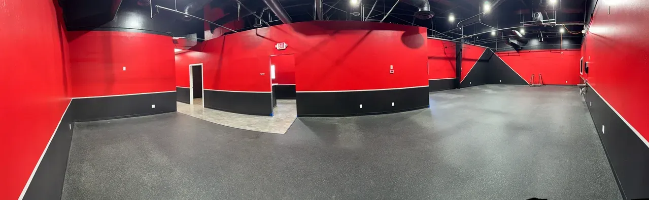Spacious gym floor with signature red walls and black industrial ceiling