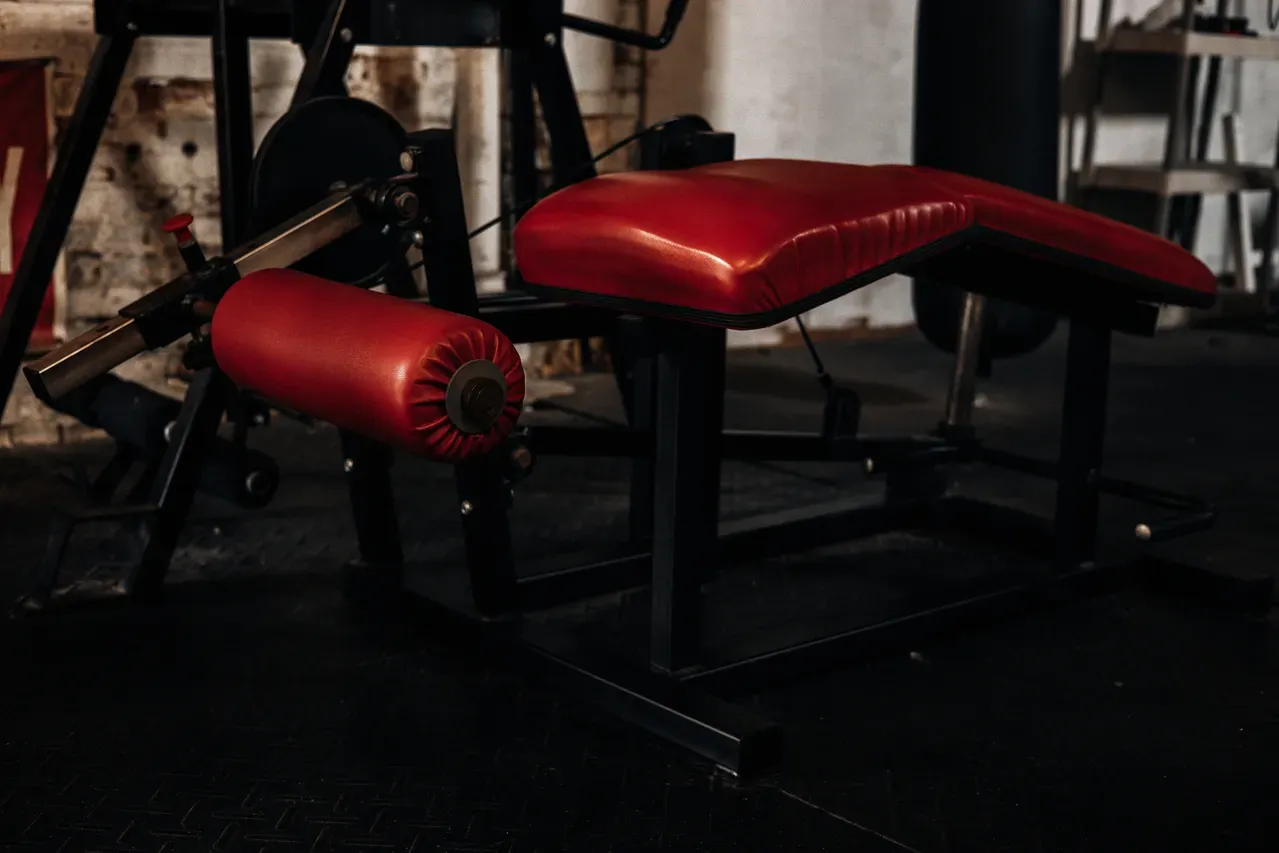 Premium red leather upholstered gym bench with leg curl attachment